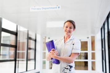 Woman in a nurses uniform stood in a hospital corridor