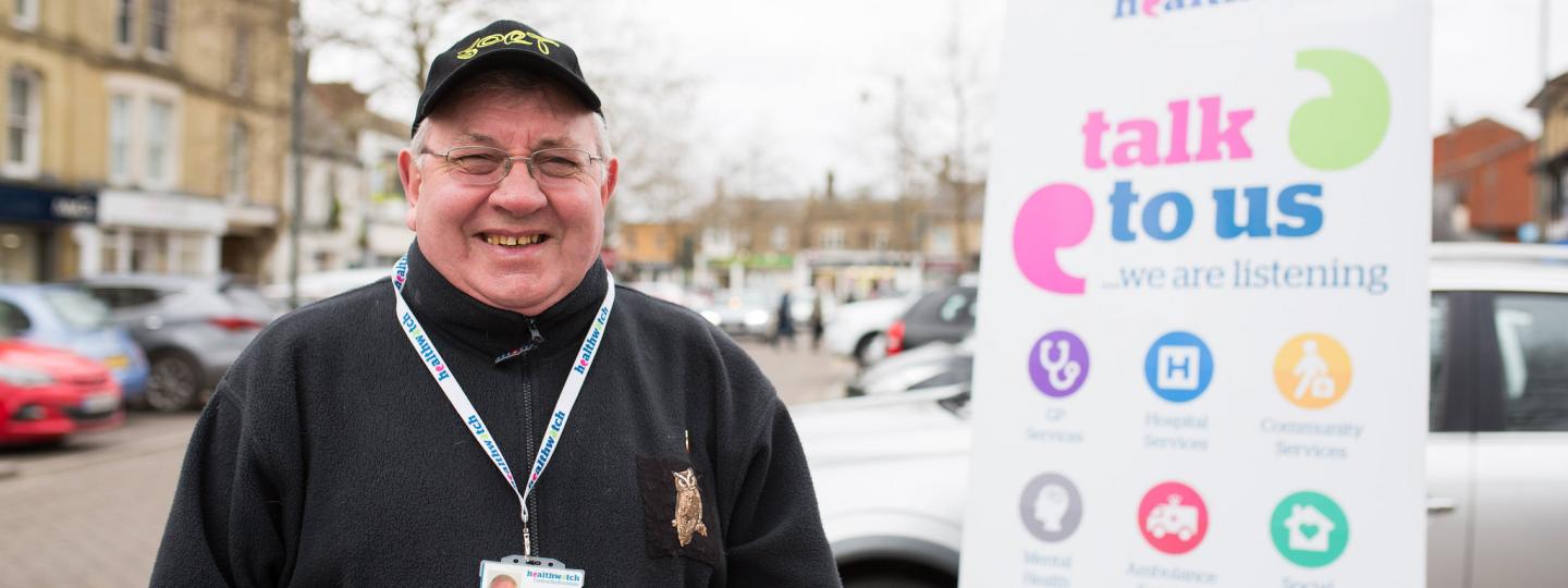 Man stood next to a Healthwatch banner