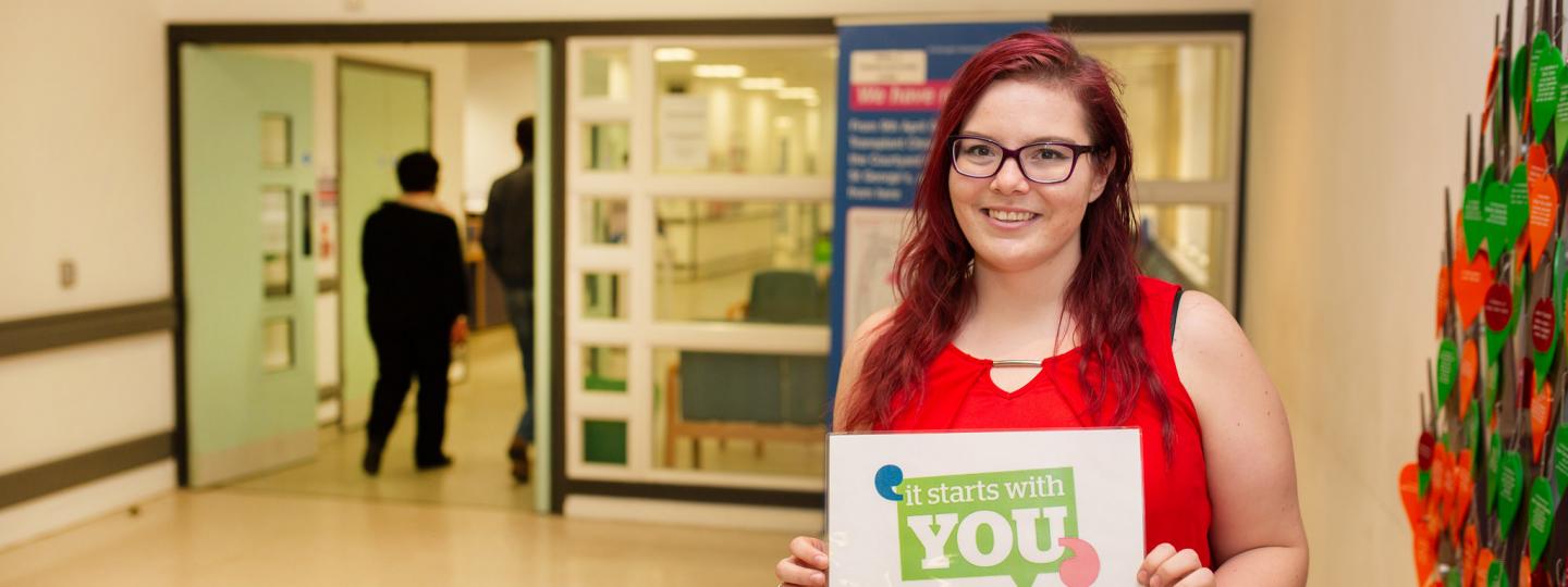 Woman holding a sign saying it starts with you