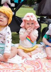Three babies at a picnic in the park sitting on a blanket
