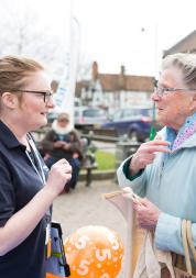 A female volunteer talking to an elderly lady at a community event. 